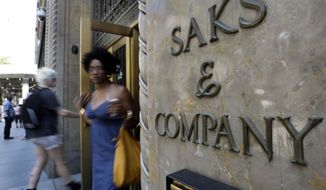 Shoppers use a Fifth Avenue entrance to Saks in New York on Monday, July 29, 2013. Saks Inc. agreed to be acquired by Hudson&#39;s Bay Co., the Canadian parent of upscale retailer Lord &amp; Taylor, for about $2.4 billion in a deal that will bring luxury to more North American locales. (AP Photo/Richard Drew)