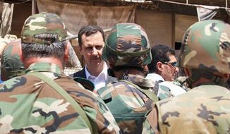 This image posted on the Syrian presidency’s official Facebook page on Thursday, Aug. 1, 2013, purports to show Syrian President Bashar Assad talking with soldiers in Darya, Syria, on his first known public trip outside Damascus, the capital, since March 2012. (Associated Press)
