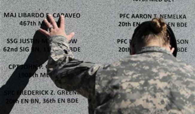 Staff Sgt. Joy Clark of the 467th Combat Stress Control Detachment takes a moment to run her fingers over the engravings of the names of her fellow soldiers at a ceremony commemorating the one-year anniversary of the worst mass shooting on a U.S. military base, in Fort Hood, Texas, on Nov. 5, 2010. Maj. Nidal Hasan is charged in the 2009 shooting rampage at Fort Hood that left 13 dead and more than 30 others wounded. (Associated Press) **FILE**