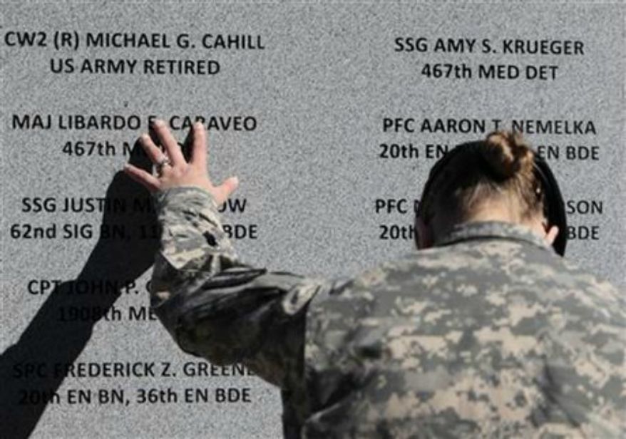 Staff Sgt. Joy Clark of the 467th Combat Stress Control Detachment takes a moment to run her fingers over the engravings of the names of her fellow soldiers at a ceremony commemorating the one-year anniversary of the worst mass shooting on a U.S. military base, in Fort Hood, Texas, on Nov. 5, 2010. Maj. Nidal Hasan is charged in the 2009 shooting rampage at Fort Hood that left 13 dead and more than 30 others wounded. (Associated Press) **FILE**