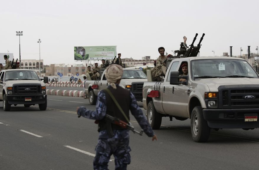 **FILE** A Yemeni police officer (front), loyal to Yemen's ousted President Ali Abdullah Saleh, takes part along with fellow Republican Guard troops during a demonstration demanding their reward, while armored vehicles patrol around the presidential palace in Sanaa, Yemen, on Aug. 2, 2013. A military official said clashes erupted in the Yemeni capital when a group of soldiers who had joined a mutiny tried to storm the presidential palace. (Associated Press)