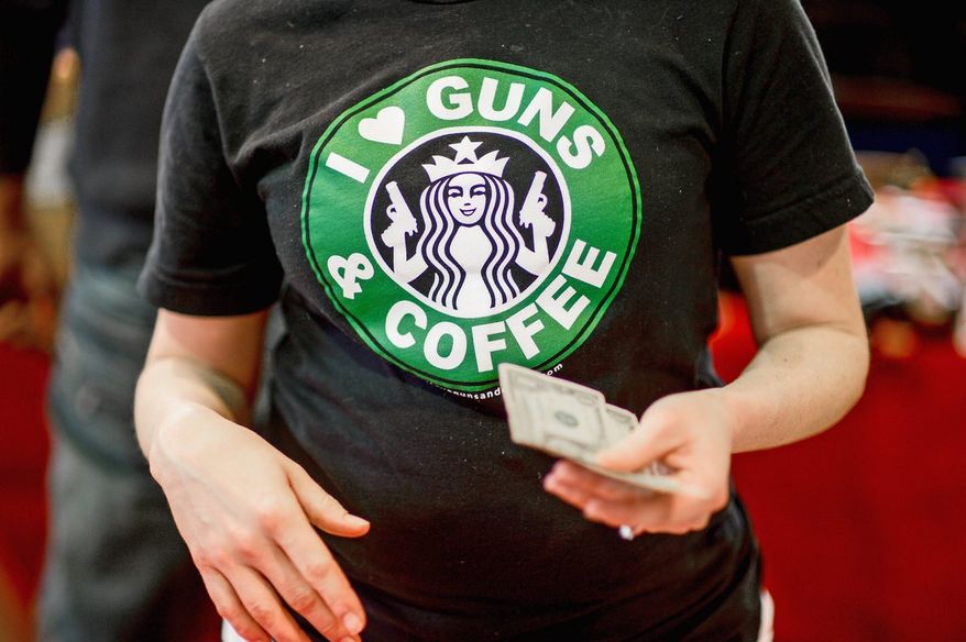 Sandy Early, with Free State Militia Firearms, sells T-shirts that modify the Starbucks logo at a gun show in Annapolis earlier this year. (Andrew Harnik/The Washington Times)