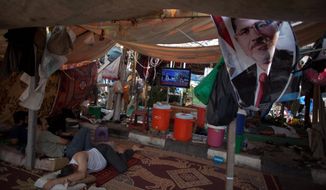Supporters of Egypt&#39;s ousted President Mohammed Morsi rest in a tent watching TV on Tuesday outside Rabaah al-Adawiya mosque, where protesters have installed a camp and held daily rallies at Nasr City in Cairo. Instead of rushing for the exits, Islamist supporters are replacing tents with wooden huts in their Cairo encampment. (Associated Press)