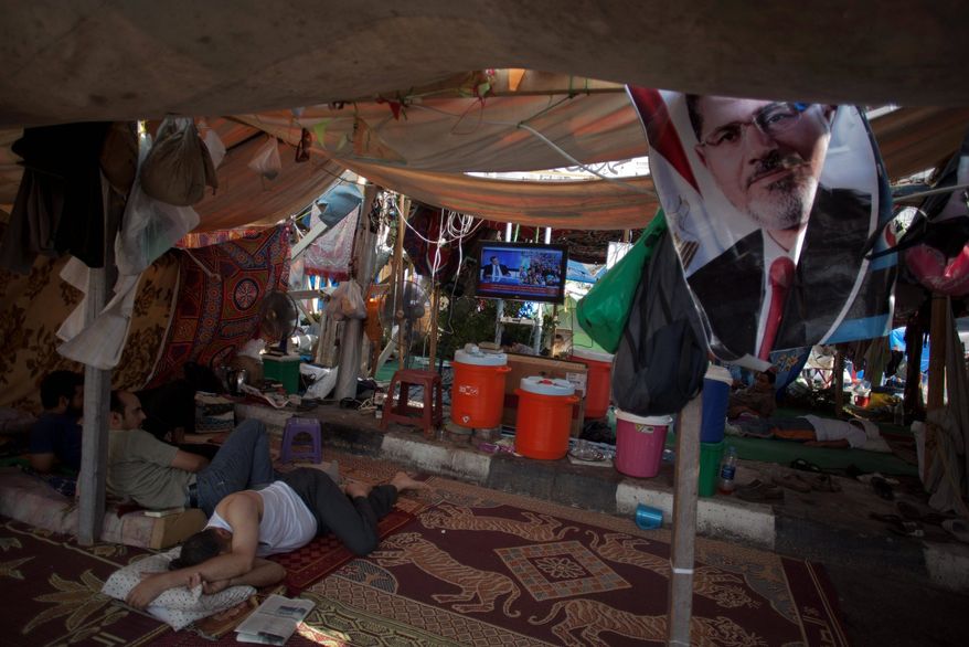 Supporters of Egypt's ousted President Mohammed Morsi rest in a tent watching TV on Tuesday outside Rabaah al-Adawiya mosque, where protesters have installed a camp and held daily rallies at Nasr City in Cairo. Instead of rushing for the exits, Islamist supporters are replacing tents with wooden huts in their Cairo encampment. (Associated Press)