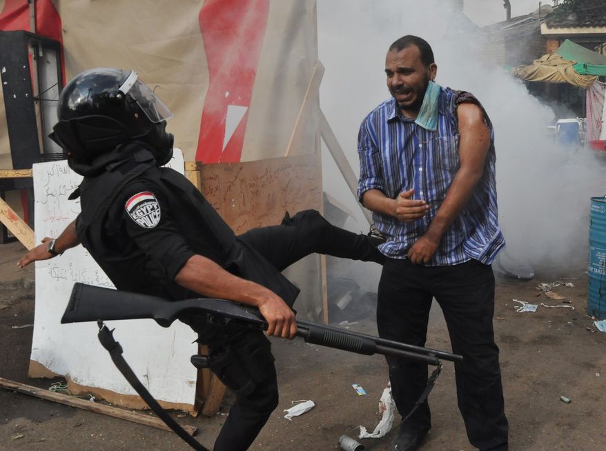 An Egyptian security force kicks a supporter of ousted Islamist President Mohammed Morsi as they clear a sit-in camp set up near Cairo University in Cairo's Giza district on Aug. 14, 2013. Egyptian police in riot gear swept in with armored vehicles and bulldozers to clear the sit-in camp and the other encampment set up by supporters of Morsi, showering them with tear gas as the sound of gunfire rang out. (Associated Press)