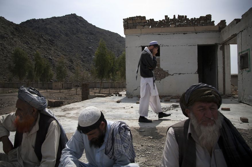 **FILE** Afghan men sit among the debris of their destroyed school in the village of Budyali in the Nangarhar province of Afghanistan on March 19, 2013. Taliban militants attacked the nearby district headquarters in July 2011, then took refuge in the school. The Afghan National Army requested help from coalition forces, who responded with drones, fighter jets and rockets, leaving the school destroyed, according to village elders. (Associated Press)