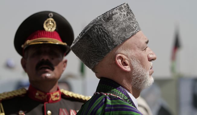Afghan President Hamid Karzai (foreground) inspects the guard of honor during Independence Day celebrations at the Defense Ministry in Kabul, Afghanistan, on Monday, Aug 19, 2013. Mr. Karzai and Cabinet members attended a parade on Monday to mark the event, which commemorates the day Afghanistan signed a treaty with Britain in 1919 making it independent. (AP Photo/Rahmat Gul)