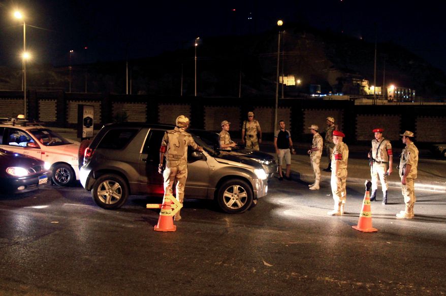 ** FILE ** Egyptian army forces search vehicles at a checkpoint during curfew in the Nasr City section of Cairo on Monday, Aug. 19, 2013. The capital remained under a state of emergency and a dusk-to-dawn curfew. (AP Photo/Ahmed Gomaa)
