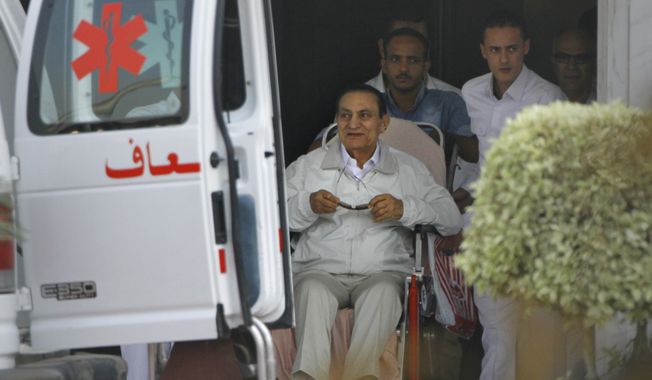 Former Egyptian President Hosni Mubarak (seated), 85, is escorted by medical and security personnel into an ambulance to be taken by helicopter ambulance from Maadi Military Hospital to the Cairo Police Academy for trial on Sunday, Aug. 25, 2013, in Cairo. Mr. Mubarak, under house arrest after being released from detention last week, is being retried on charges of complicity in the killings of protesters during the 2011 Egyptian uprising. (AP Photo/Amr Nabil)