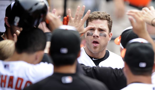 Baltimore Orioles' Chris Davis celebrates his two-run home run in the dugout during the eighth inning of a baseball game against the Colorado Rockies, Sunday, Aug. 18, 2013, in Baltimore. The Orioles won 7-2. (AP Photo/Nick Wass)