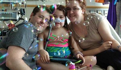 **FILE** In this May 30, 2013, file photo provided by the Murnaghan family, Sarah Murnaghan (center), celebrates the 100th day of her stay in Children&#39;s Hospital of Philadelphia with her parents Fran and Janet. (Associated Press)