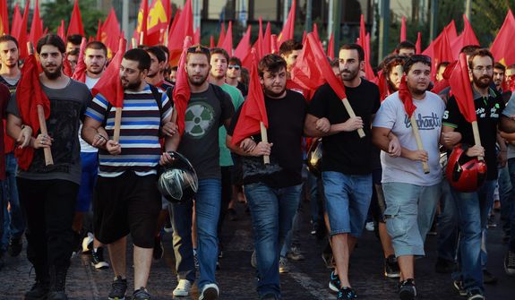 Members of the Greek Communist Party march with flags,  in front of the Parliament in Athens during an protest against any military action by the U.S. and its allies against Syria,  on Thursday Aug. 29, 2013. (AP Photo/Dimitri Messinis)