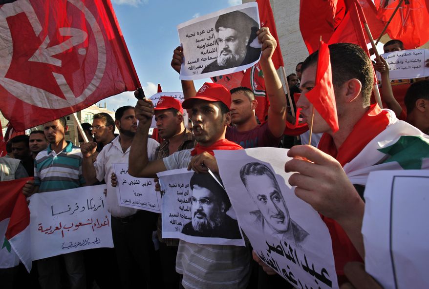Palestinian supporters of the Popular Front for the Liberation of Palestine wave their red flags in Rafah Refugee Camp, southern Gaza Strip, on Sept. 3, 2013, while holding Syrian flags and pictures of late Egyptian President Gamal Abdel-Nasser and Hezbollah leader Hassan Nasrallah during a protest against a possible military attack by the United States on Syria, . Arabic on placards reads, "America and France are the enemies of the Arab nations, greetings from Gaza to the master of the Lebanese resistance, the leader Hassan Nasrallah and greetings to the Syrian, Lebanese and Palestinian resistance." (Associated Press)