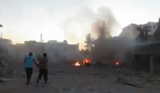 In this image taken from video obtained from the Shaam News Network, which has been authenticated based on its contents and other AP reporting, Syrian men walk near damages after a bomb hit Binnish town, Idlib province, Syria, on Sept. 5, 2013. (Associated Press/Shaam News Network via AP video)