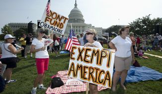 ** FILE ** Linda Norman (right) and Joanna Galt, both from Florida, hold their banners during a &quot;Exempt America from Obamacare&quot; rally on the West Lawn of the Capitol in Washington on Sept. 10, 2013. (Associated Press)