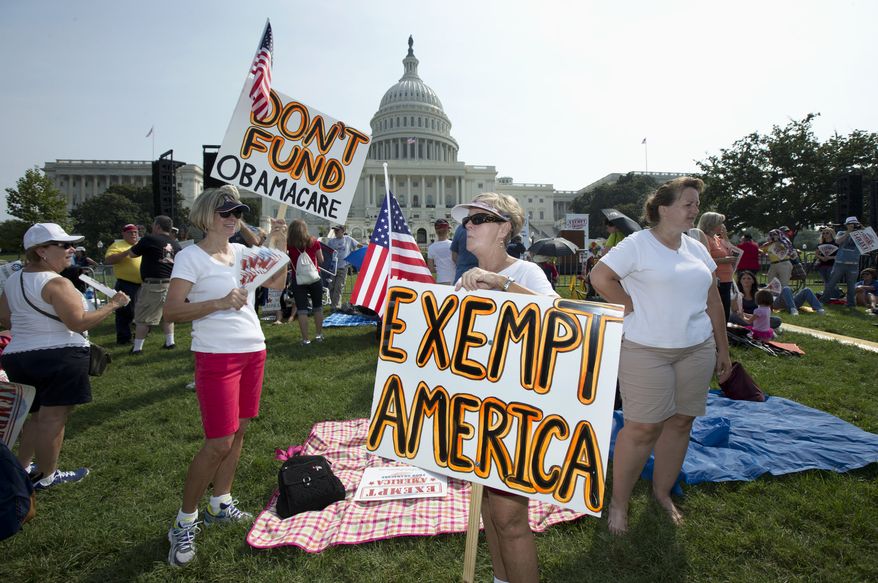 ** FILE ** Linda Norman (right) and Joanna Galt, both from Florida, hold their banners during a "Exempt America from Obamacare" rally on the West Lawn of the Capitol in Washington on Sept. 10, 2013. (Associated Press)