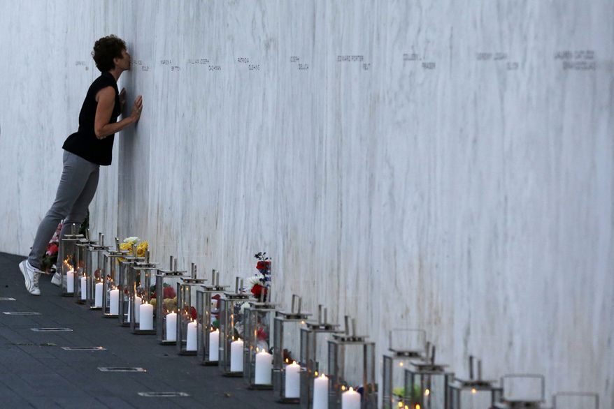 A visitor kisses a name on the wall containing the 40 names of the crew and passengers of Flight 93 at the Flight 93 National Memorial during a candlelight remembrance on Tuesday, Sept. 10, 2013. (AP Photo/Gene J. Puskar)