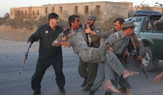 Afghan security personnel assist an injured police after a suicide car bombing and a gunfight near the U.S. Consulate in Herat Province, west of Kabul, Afghanistan, Friday, Sept. 13, 2013. (AP Photo/Hoshang Hashimi)