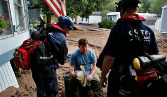 Suffering from dehydration, local resident Fred Rob gets help from emergency responders after floods left homes and infrastructure in a shambles, in Lyons, Colo., Friday Sept. 13, 2013. (AP Photo/Brennan Linsley)