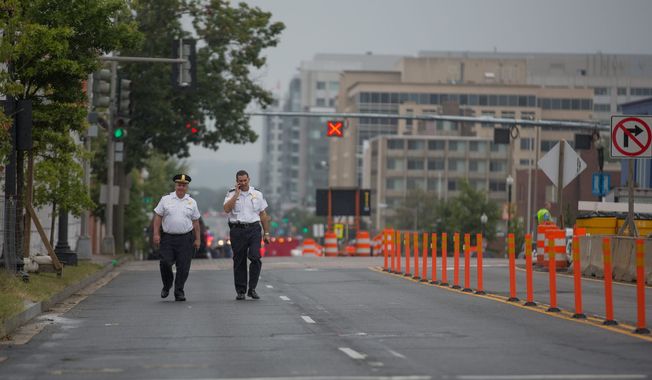 Two police officers walk down M st. outside of the Navy Yard. Recreation centers and parks in the area also closed as police, reporters and onlookers snarled traffic. (Andrew S Geraci/The Washington Times)