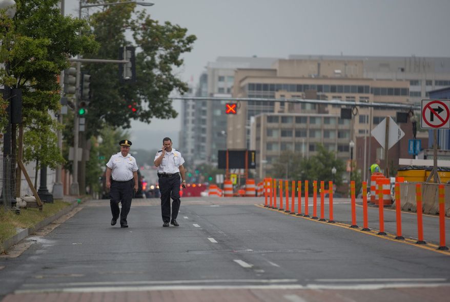 Two police officers walk down M st. outside of the Navy Yard. Recreation centers and parks in the area also closed as police, reporters and onlookers snarled traffic. (Andrew S Geraci/The Washington Times)