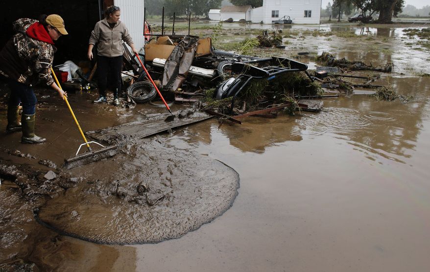 ** FILE ** Genevieve Marquez (left) and Miranda Woodard help salvage and clean property in an area inundated after days of flooding in Hygeine, Colo., on Monday, Sept. 16, 2013. (AP Photo/Brennan Linsley)