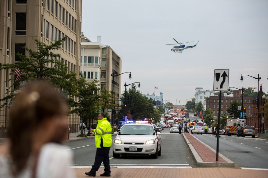 A helicopter circles over police outside the Washington Navy Yard as workers are evacuated from the area and police search for a gunman on Monday, Sept. 16, 2013. (Andrew S. Geraci/The Washington Times)