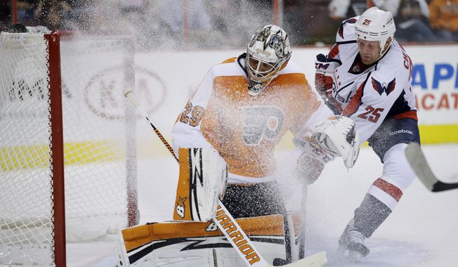 Philadelphia Flyers goalie Ray Emery, left, blocks a shot as Washington Capitals' Jason Chimera slides in during the first period of a preseason NHL hockey game, Monday, Sept. 16, 2013, in Philadelphia. (AP Photo/Matt Slocum)