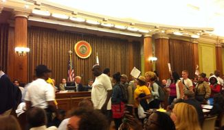 Protesters exit the D.C. Council chambers after members failed to override the mayor&#39;s veto of the &quot;living wage&quot; bill. (Andrea Noble/The Washington Times)