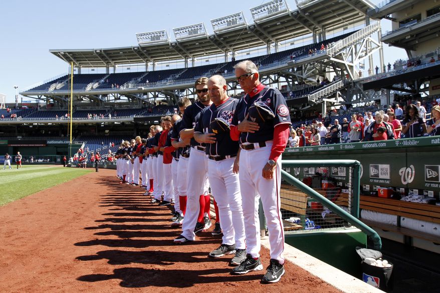 Holding Navy hats, Washington Nationals manager Davey Johnson, right, and others observe a moment of silence before a baseball game against the Atlanta Braves at Nationals Park Tuesday, Sept. 17, 2013, in Washington. The Nationals wore Navy hats, presented to them by Adm. James A. Winnefield, vice-chairman of the Joint Chiefs of Staff, before the game, to honor those killed and injured in the attack Monday at the nearby Washington Navy Yard. (AP Photo/Alex Brandon)