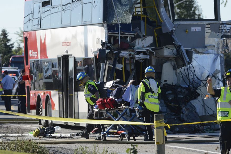 A bus passenger is taken to an ambulance following a collision between a Via Rail train and city transit bus in Ottawa's west end on Wednesday, Sept. 18, 2013. (AP Photo/The Canadian Press, Adrian Wyld)