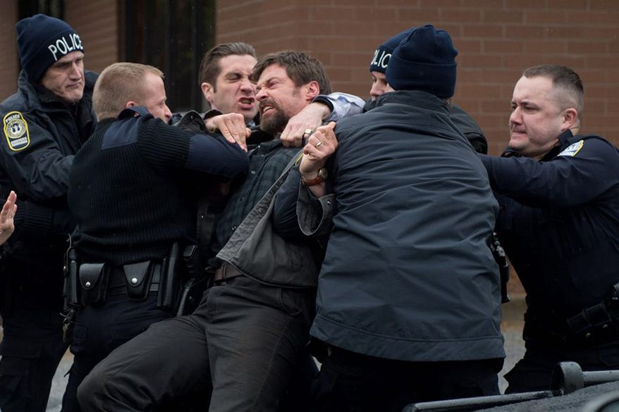 Hugh Jackson, playing the father of a missing girl, has to be restrained by police in "Prisoners." Jake Gyllenhaal (third from left) is the police detective trying to solve the case. (WARNER BROTHERS PICTURES VIA ASSOCIATED PRESS)