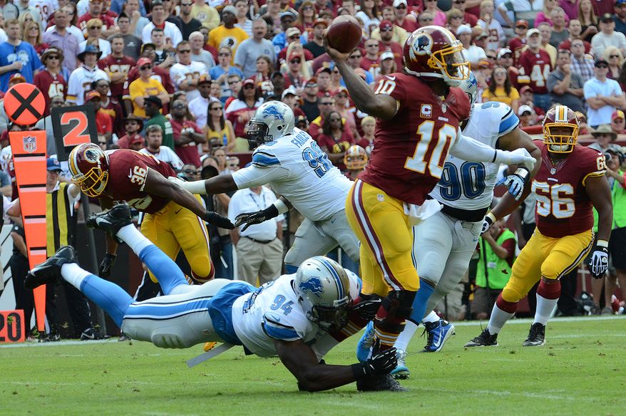 Washington Redskins quarterback Robert Griffin III (10) is rushed by Detroit Lions defensive end Ezekiel Ansah (94) as he throws and incomplete pass during the first quarter as the Washington Redskins play the Detroit Lions at FedExField, Landover, Md., September 22, 2013. (Dan DeCook/Special for The Washington Times)