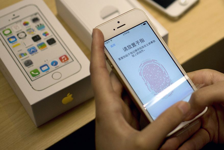 A customer configures the fingerprint scanner technology built into the Apple iPhone 5S at a company store in the Wangfujing shopping district of Beijing on Friday, Sept. 20, 2013. (AP Photo/Andy Wong)