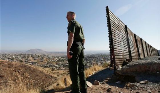 ** FILE ** U.S. Border Patrol agent Jerry Conlin looks out over Tijuana, Mexico, behind, along the old border wall along the U.S. - Mexico border, where it ends at the base of a hill in San Diego, June 13, 2013. (AP Photo/Gregory Bull, File)
