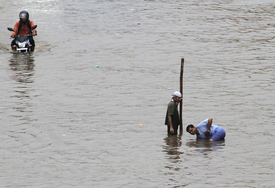Indians clean blocked sewerage line to drain out flooded water from a road after heavy rains lashed, in Ahmadabad, India, Wednesday, Sept. 25, 2013. Massive flooding has forced 15,000 people to evacuate villages in the west Indian state of Gujarat where heavy rains and swollen rivers have inundated cities and closed off roads and railway lines. (AP Photo/Ajit Solanki)