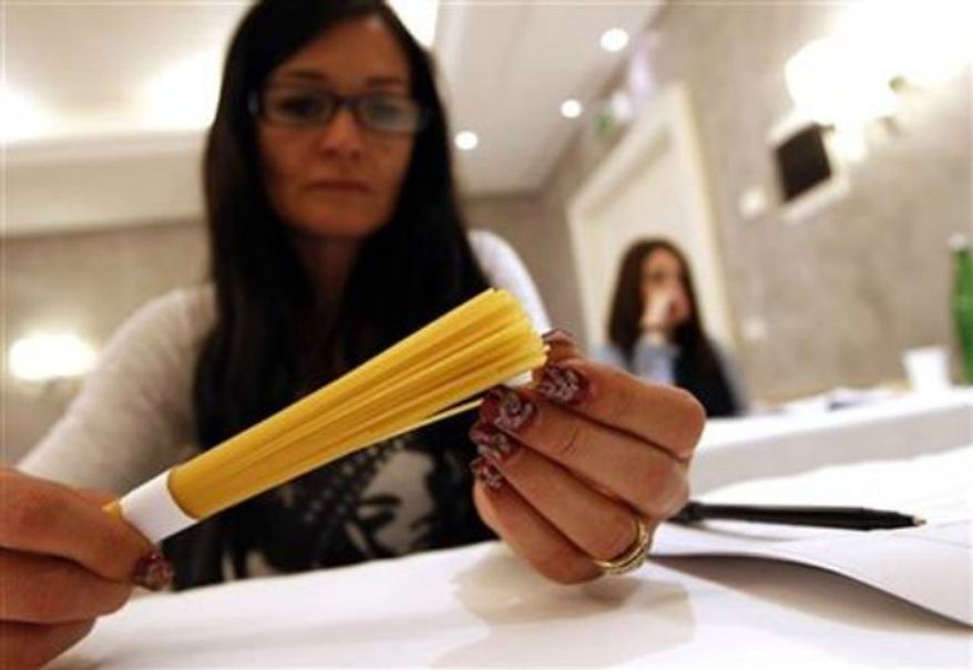 ** FILE ** A woman touches pasta in a hotel conference room in Rome, May 18, 2012. (Associated Press)