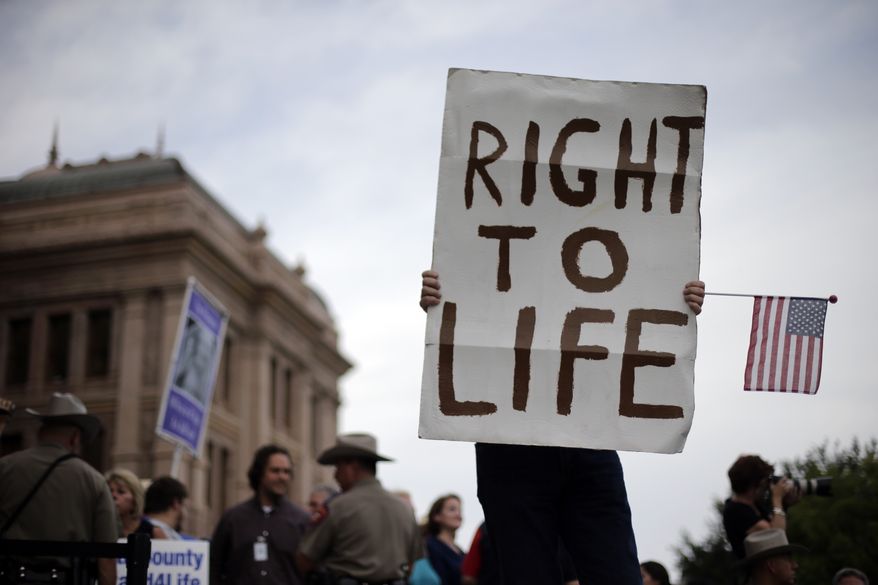 **FILE** A man holds a sign during an anti-abortion rally at the Texas Capitol in Austin on July 8, 2013. (Associated Press)