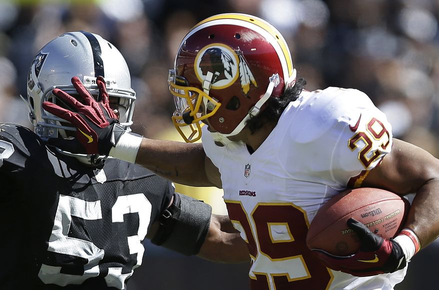 Washington Redskins running back Roy Helu stiff-arms Oakland Raiders linebacker Nick Roach (53) during the second quarter of an NFL football game in Oakland, Calif., Sunday, Sept. 29, 2013. (AP Photo/Marcio Jose Sanchez)
