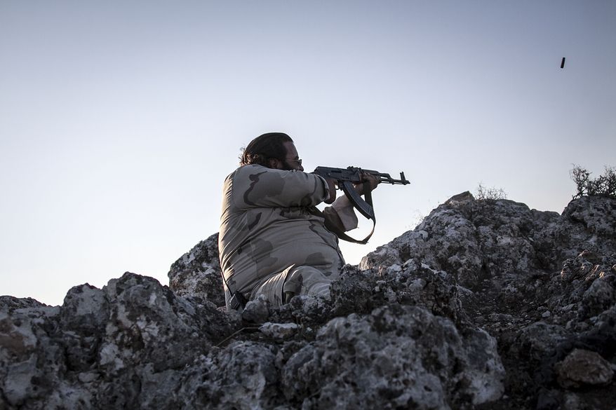 A Syrian opposition fighter aims at government forces during exchange of fire in Telata, a front-line village at the top of a mountain in the Idlib province of Syria. (AP Photo)