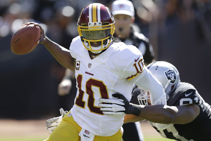 Washington Redskins quarterback Robert Griffin III (10) runs from Oakland Raiders defensive end Jack Crawford (91) during the second quarter of an NFL football game in Oakland, Calif., Sunday, Sept. 29, 2013. (AP Photo/Ben Margot)