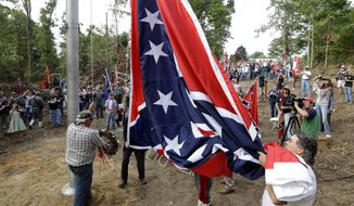 ** FILE ** Virginia Flaggers raise the Confederate battle flag near Interstate 95 in Chester, Va., on Saturday, Sept. 28, 2013. Hundreds gathered in freshly cleared woods for the event, celebrated with a volley fired from the rifles of Confederate re-enactors. (AP Photo/Steve Helber)