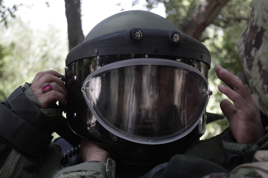 In this Tuesday, Aug 27, 2013 photo, Afghan army soldier Ali Raza, 30, adjusts his demeaning gear during an IED, or improvised explosive device, defusing training exercise in Jalalabad, east of Kabul, Afghanistan. After 12 years of war, roadside bombs are the No. 1 killer, claiming thousands of lives every year. As foreign troops wind down operations in preparation for their withdrawal at the end of 2014 insurgents are using an ever larger number of these explosives to assert their grip and recapture territory. (AP Photo/Rahmat Gul)