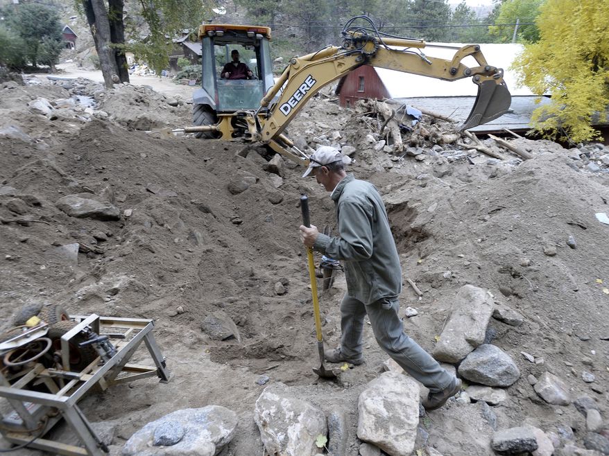 Backhoe operator Rick Benson works with Randy Walter, at center, to make a path to a propane tank while cleaning up flood damage on Thursday, Oct. 3,2013, in Salina, Colo. The flooding damaged or destroyed nearly 1,800 homes in Colorado. (AP Photo/The Daily Camera, Jeremy Papasso) NO SALES