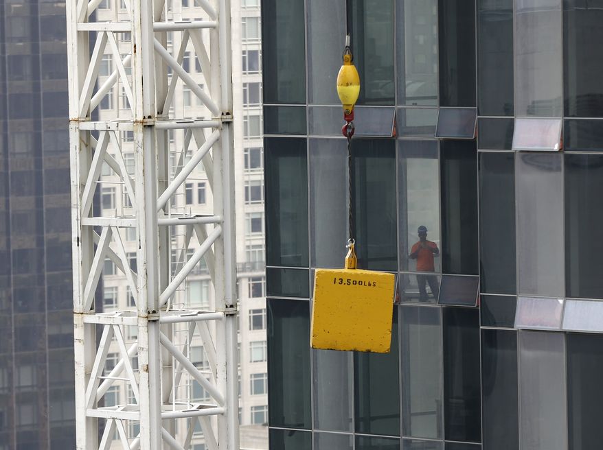 A man looks at a load stuck suspended above the street in New York, Monday, Oct. 7, 2013. Officials have closed West 57th Street between 6th and 7th avenues in Manhattan after a tower crane hoisting a load apparently got stuck about 20 floors up. A construction supervisor says the crane is the same one crane whose boom dangled dangerously nearly a year ago during Superstorm Sandy. (AP Photo/Seth Wenig)