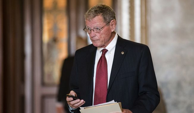 ** FILE ** Sen. James M. Inhofe, an Oklahoma Republican who is his party&#x27;s ranking member on the Senate Armed Services Committee, leaves the Senate after assisting Sen. Ted Cruz, Texas Republican, with his overnight fight on the floor against the Affordable Care Act, popularly known as Obamacare, at the Capitol in Washington on Wednesday, Sept. 25, 2013. (AP Photo/J. Scott Applewhite)