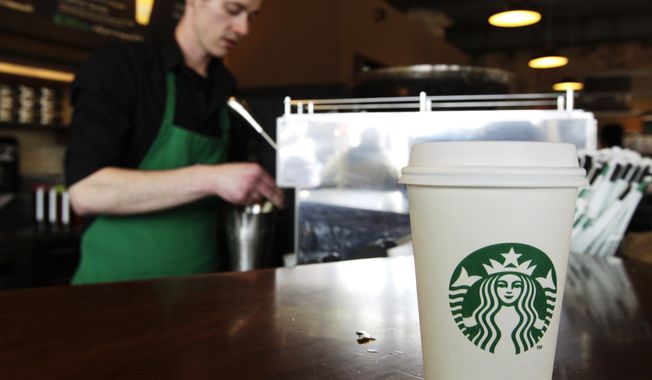 ** FILE ** A Starbucks drink awaits customer pickup as barista Josh Barrow prepares another in Seattle on  Friday, April 27, 2012. (AP Photo/Ted S. Warren)