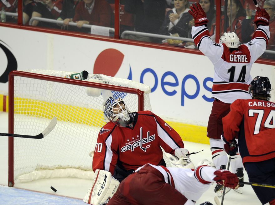 Washington Capitals goalie Braden Holtby (70) reacts after Carolina Hurricanes center Nathan Gerbe (14) scored a goal against him during the third period an NHL hockey game, Thursday, Oct. 10, 2013, in Washington. The Hurricanes won 3-2. Also seen is Washington Capitals defenseman John Carlson (74). (AP Photo/Nick Wass)