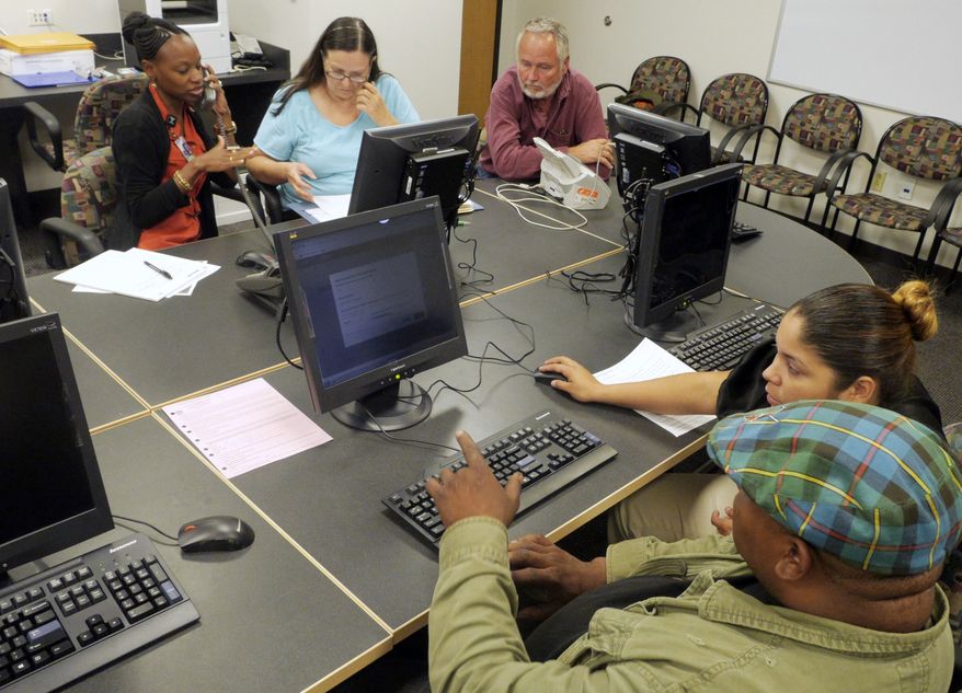 ** FILE ** Parkland Memorial Hospital financial counselor Kaneaka Guidry, back left, helps Cathleen and Jerry Brown sign up for insurance under the Affordable Care Act while Vyncent Bosh, front left, receives help from Tiffany Ruiz, Parkland Memorial Hospital financial counselor, front right, on Friday, Oct. 11, 2013, in Dallas. (AP Photo/The Dallas Morning News, Ron Baselice)