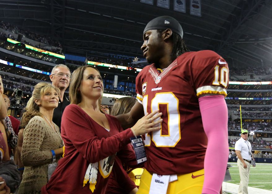 Washington Redskins quarterback Robert Griffin III (10) hugs his wife Rebecca Liddicoat, left, after warming up before an NFL football game against the Dallas Cowboys, Sunday, Oct. 13, 2013, in Arlington, Texas. (AP Photo/LM Otero)